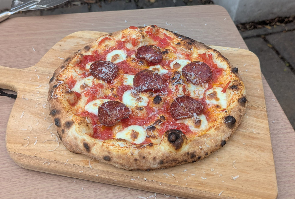 Pepperoni pizza on a wooden chopping board